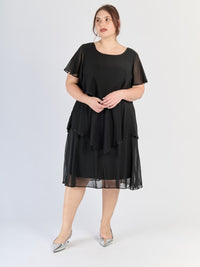 Vestito nero da sera, silhouette avvolgente con strati e maniche svettanti