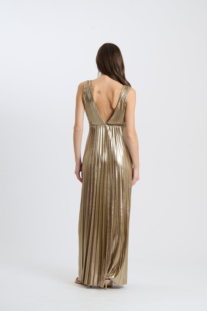 abito da sera dorato, lungo, senza maniche, plissé e scollatura a V, in un set fotografico.