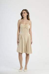 Donna con abito beige a spalline, calore e sofisticatezza neutra.