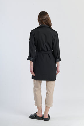 Trench nero slim, tessuto lucido per un’eleganza notturna.