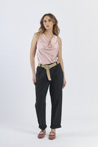 Outfit con top satinato rosa e pantaloni neri, cinghia in tonalità neutra