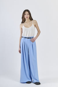 Outfit con top bianco e pantaloni azzurri ampi, cinghia nera slim