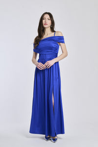 Donna con abito lungo bluette, spalline scollate, fascia in vita e apertura laterale delicata.