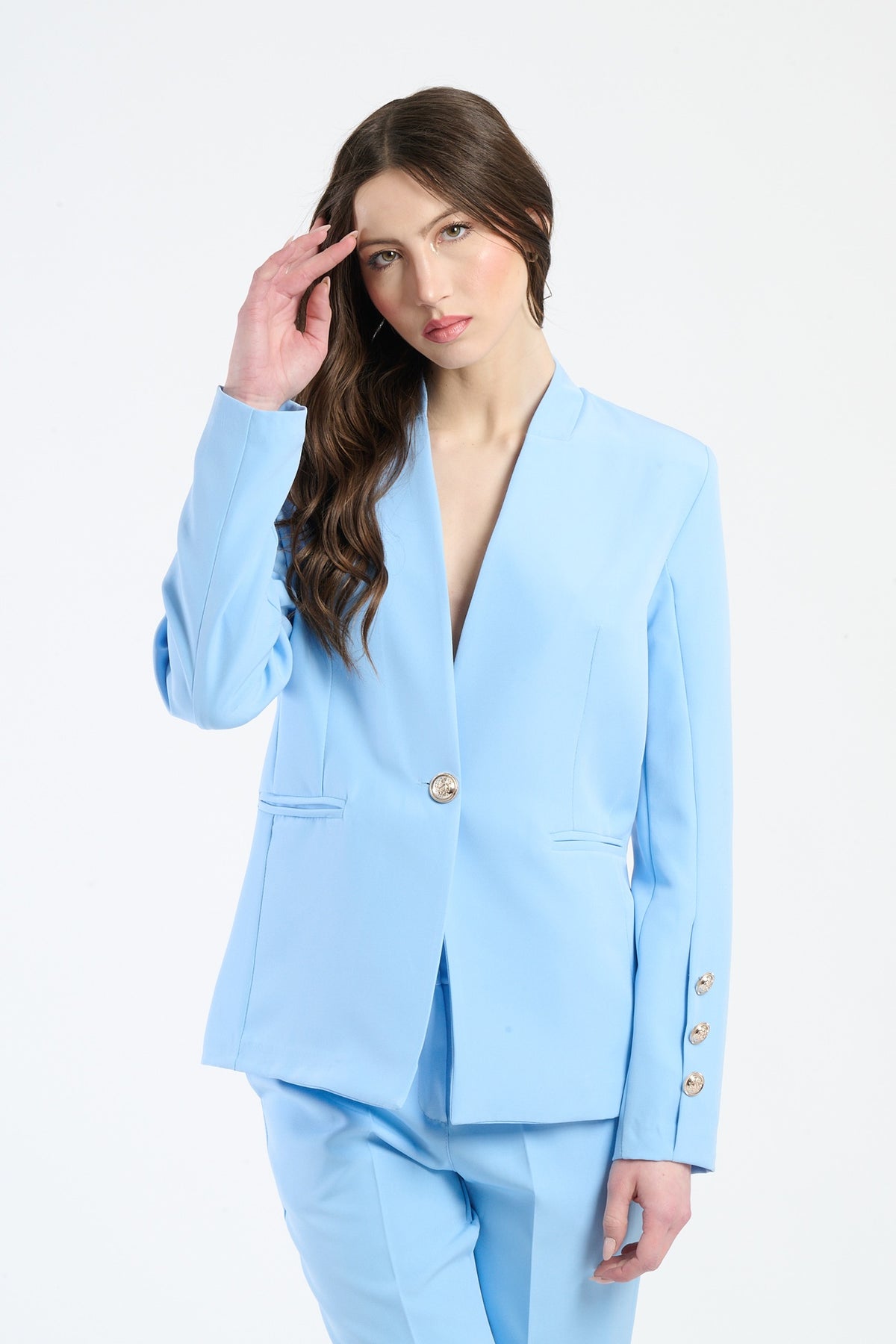 Camicia azzurra a maniche lunghe, collo a V e dettagli decorativi.
