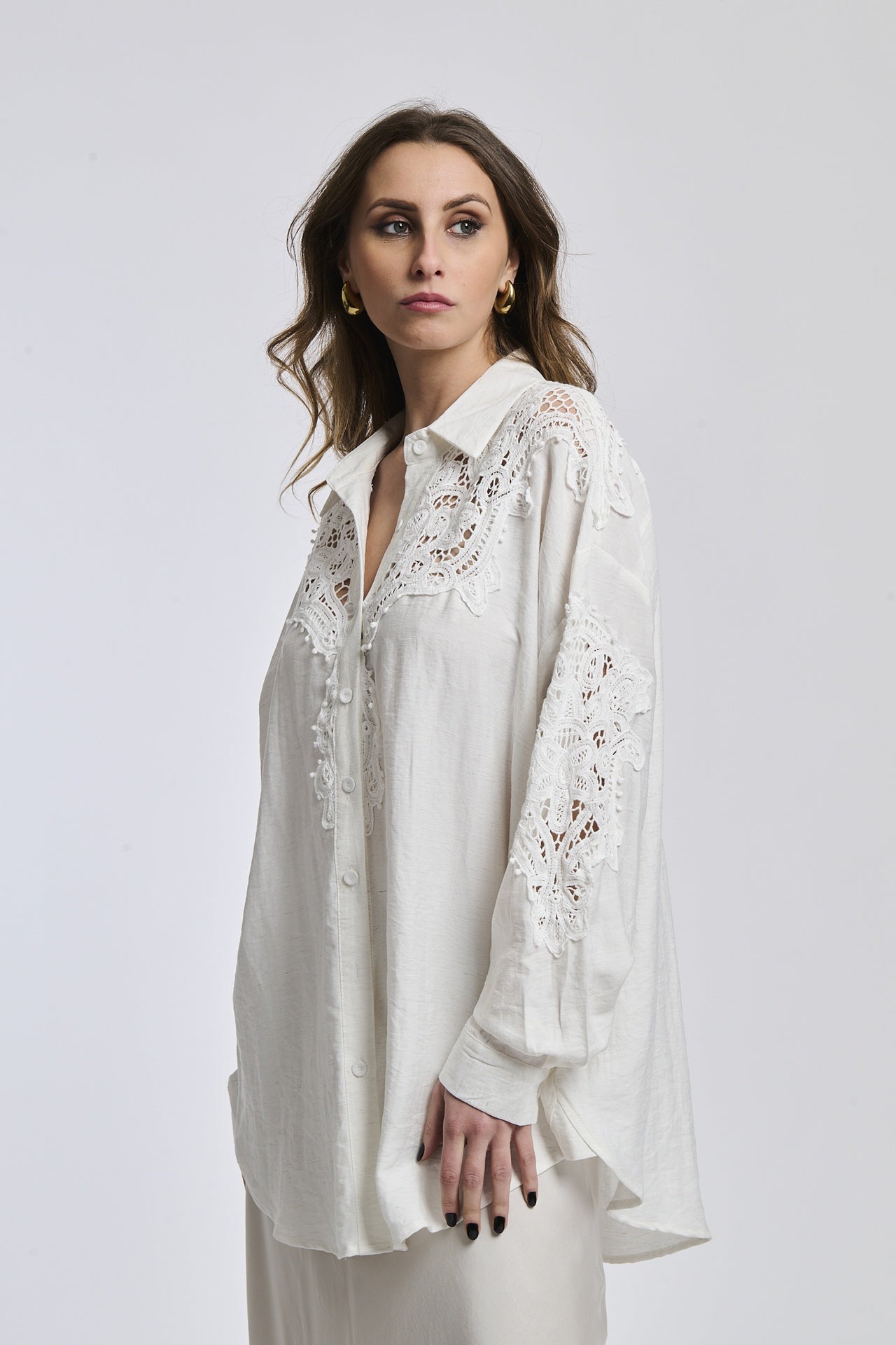 Donna indossa una camicia blu scuro con maniche lunghe e colletto a V, esprimendo un’aria di profondità e mistero.