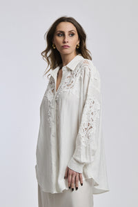 Donna indossa una camicia blu scuro con maniche lunghe e colletto a V, esprimendo un’aria di profondità e mistero.