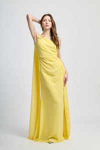 Abito lungo giallo, spalla singola, drappeggio fluido, accessorio decorativo sulla
