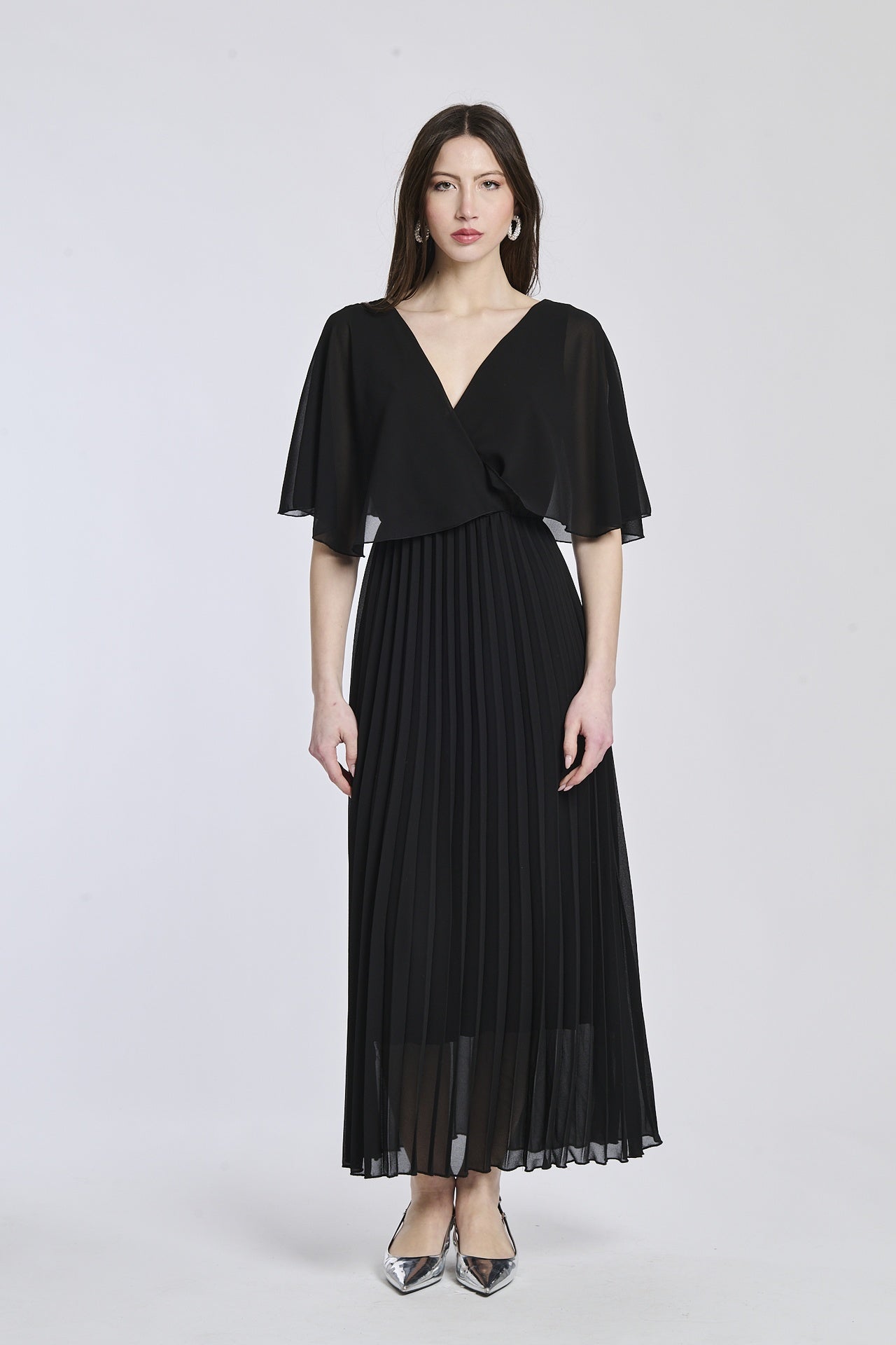 Un abito in nero con lo stesso disegno crociato e maniche a mantello, creando un'atmosfera di raffinatezza e potenza.