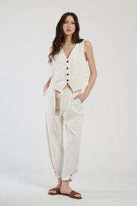 Completo bianco su una modella: gilet a bottoni e pantaloni, combinazione limpida e accattivante.