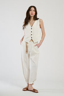 Completo bianco su una modella: gilet a bottoni e pantaloni, combinazione limpida e accattivante.