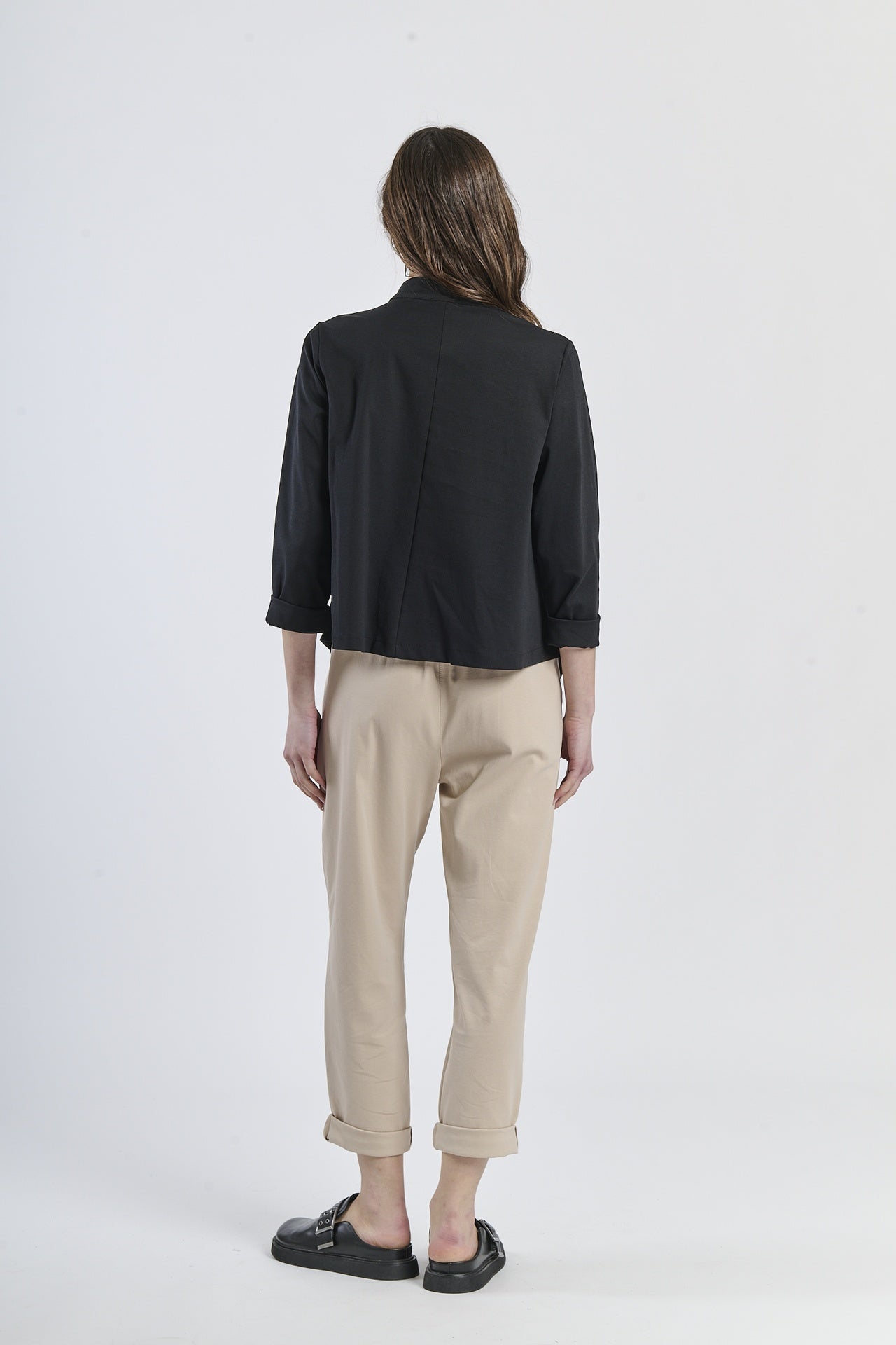 Combinazione di camicia oversize nero con bottoni laterali e pantaloni beige, stile casual-elegante
