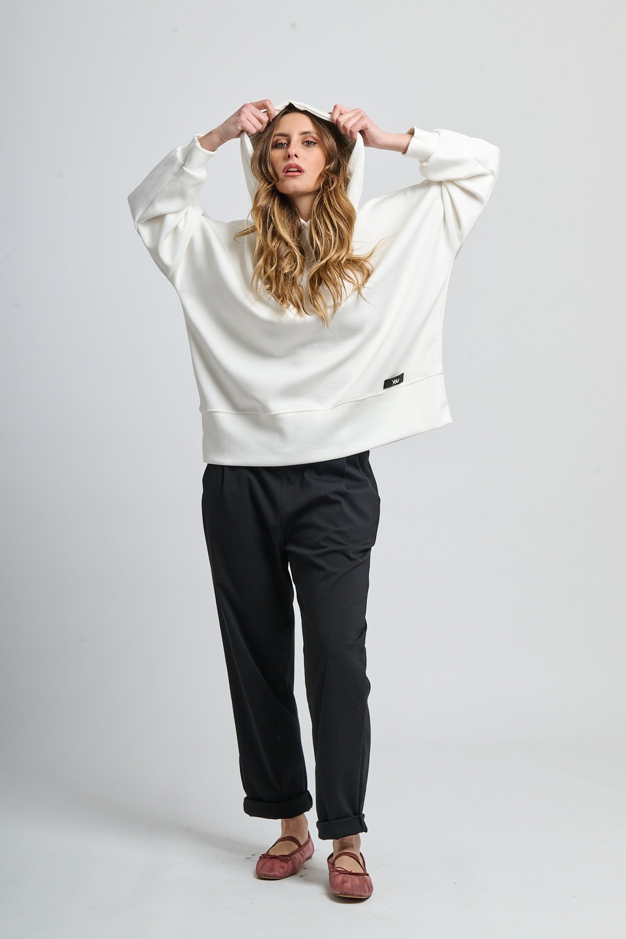 Felpa oversize bianca con cappuccio, abbinata a pantaloni neri