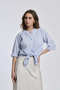 Camicia a righe navy e bianche da donna, nodo sul petto, che valorizza la silhouette con eleganza.