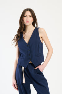Modella indossa completo navy: gilet senza maniche e pantaloni, stile sobrio e raffinato.