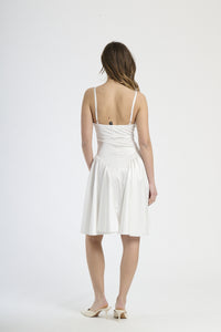 Modella indossa abito bianco, look pulito e luminoso.