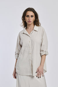 Camicia beige a righe, collo camiciera, maniche a 3/4, abbinata a pantaloni chiari.