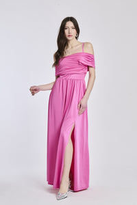 Donna con abito lungo rosa, spalline scollate, fascia in vita e apertura laterale dolce.