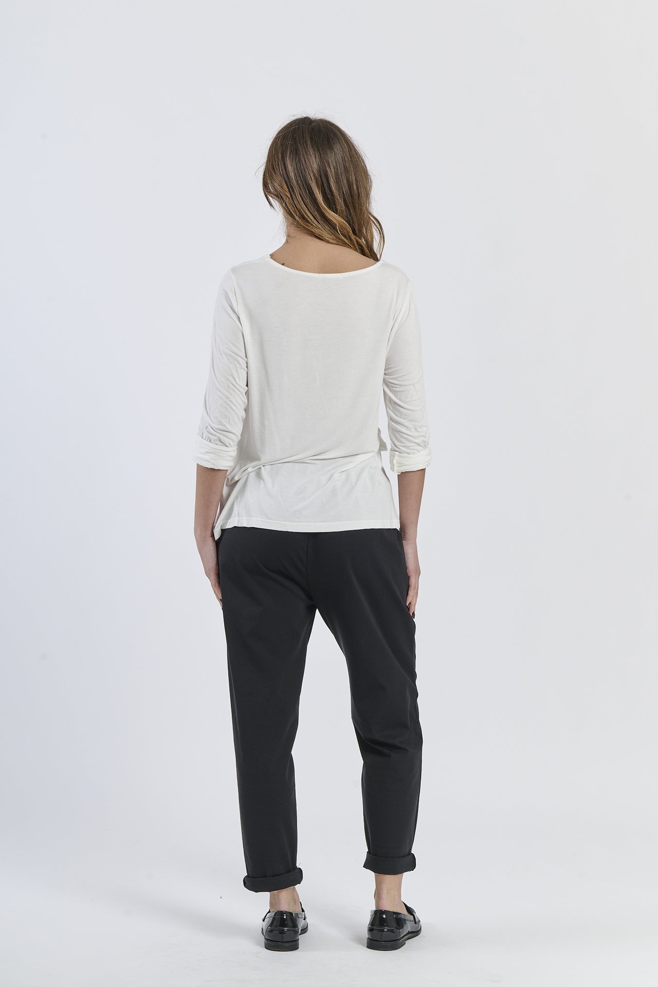 Blusa bianca a maniche 3/4, abbinata a pantaloni neri, minimalismo raffinato