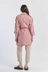 Trench rosa antico pastello, stile vintage per un’atmosfera dolce.