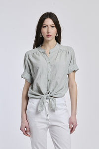 Camicia a righe militares e bianche da donna, nodo sul ventre, che dona un’aria casual e energica.