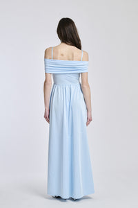 Abito azzurro a spalline scollate, taglio fluido, fascia in vita che accentua la silhouette.