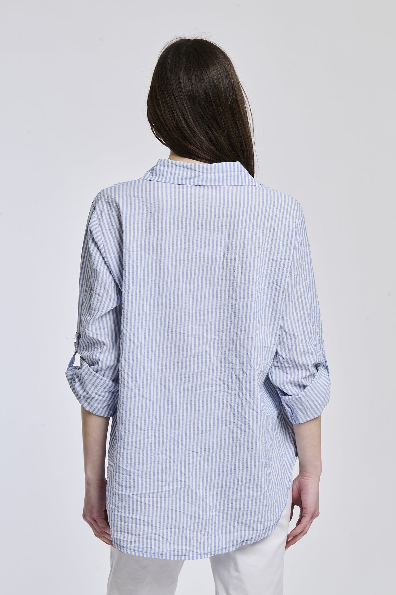 Camicia oversize navy a righe, colletto a V sfiorato, bottoni frontali e maniche arrotolate, perfetta per l’uso quotidiano.