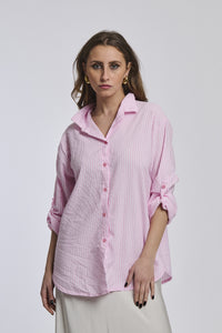  Camicia oversize rosa a righe, colletto a V sfiorato, bottoni frontali e maniche arrotolate, ideale per outfit estivi.