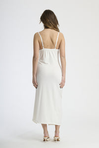 Vestito bianco in tessuto luminoso, design con ruches e spalanca, perfetto per matrimoni e eventi estivi.