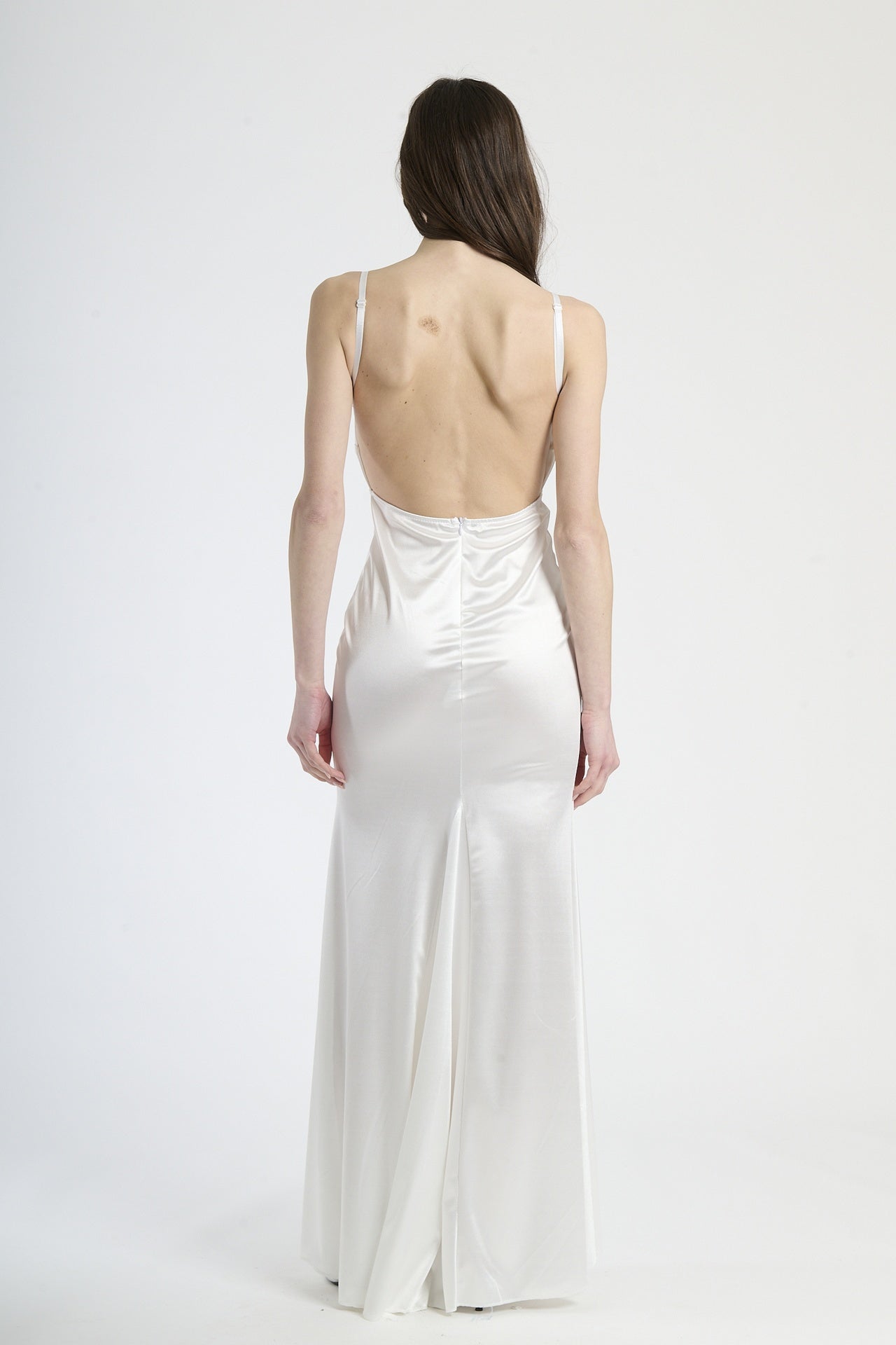 Modella indossa abito bianco a spalline sottili, stile raffinato per eventi esclusivi.