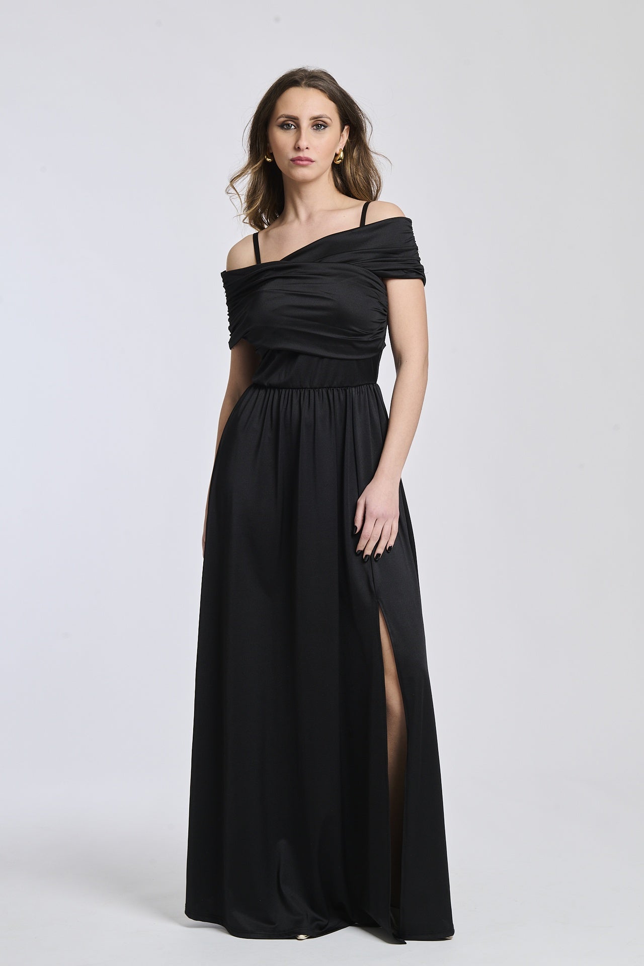 Donna indossa un abito lungo nero, spalline scollate, fascia in vita e apertura laterale affascinante.