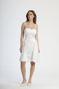 Donna con abito bianco a spalline sottili, purezza e semplicità stilosa.