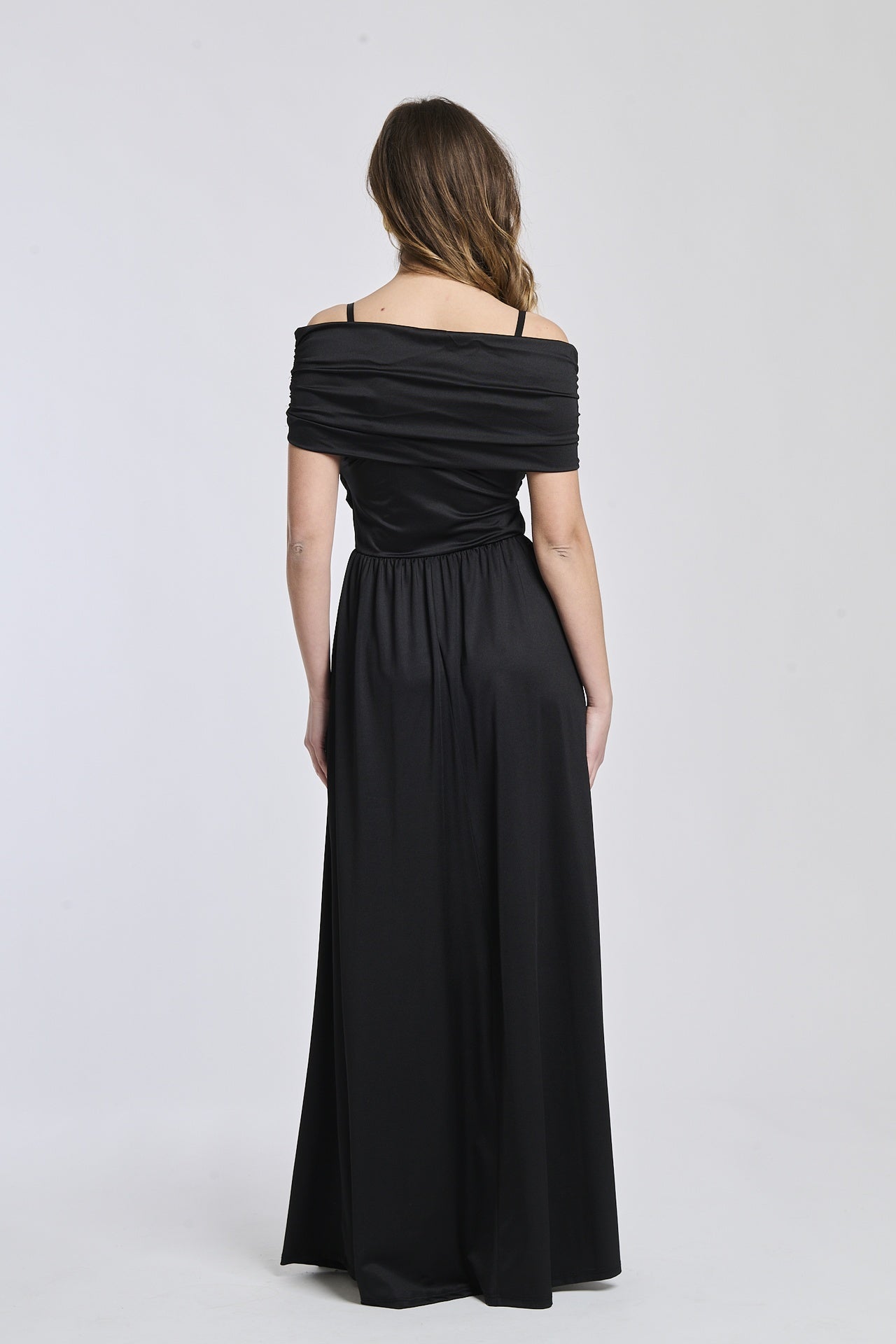 Abito nero a spalline scollate, tessuto lustrato, fascia in vita che accentua la silhouette.