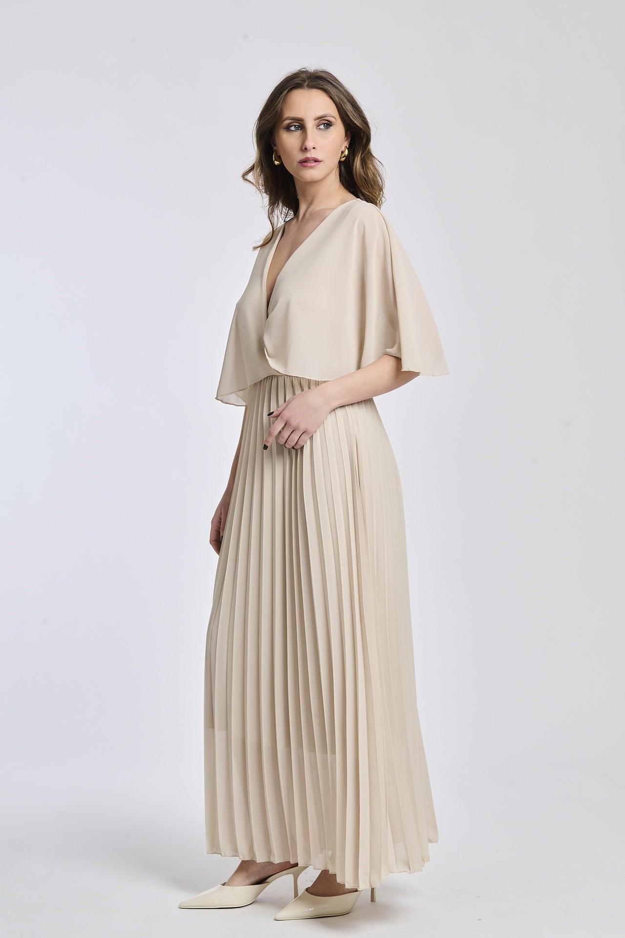 Vestito in tono beige chiaro con dettagli di falde e maniche, offrendo un look elegante e versatile.
