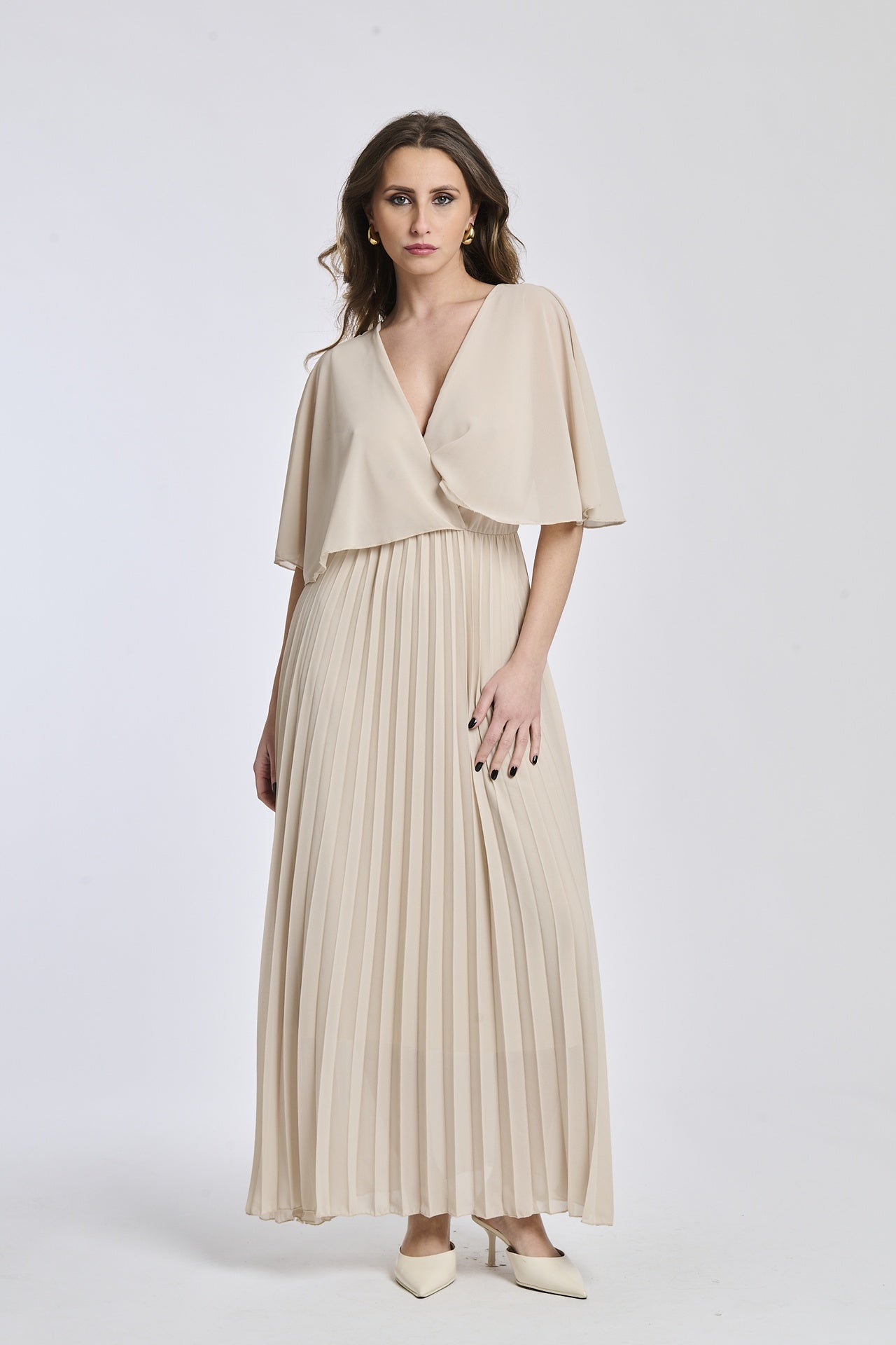 Un vestito in beige caldo, con il taglio crociato sul busto e le maniche a mantello del modello originale, che dà un senso di calma e eleganza.