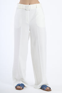 Pantaloni larghi bianchi con cintura, taglio a zampa, abbinati a sandali.