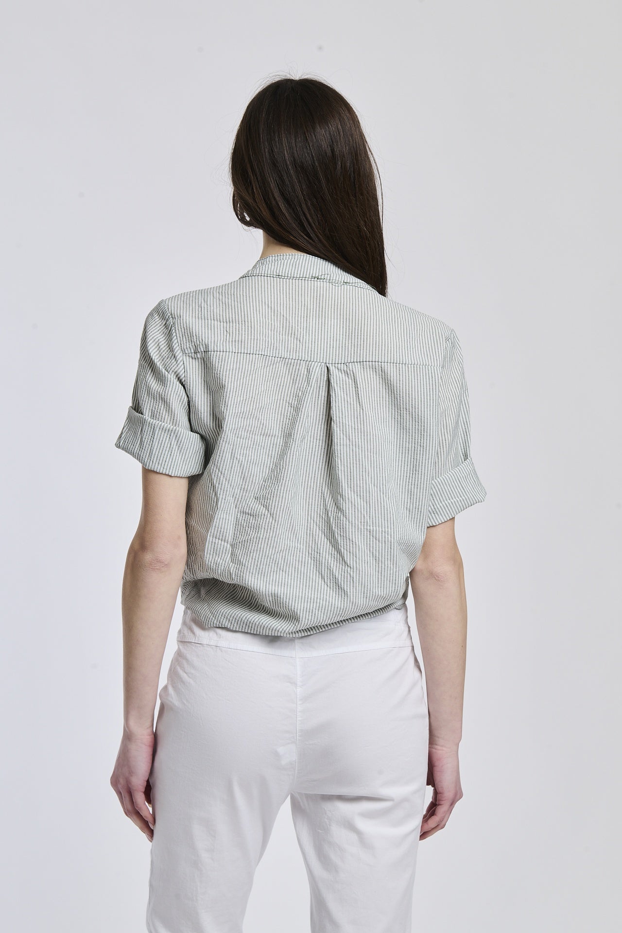 Donna con camicia a righe militare, maniche lunghe e nodo frontale, ideale per un look avventuroso.