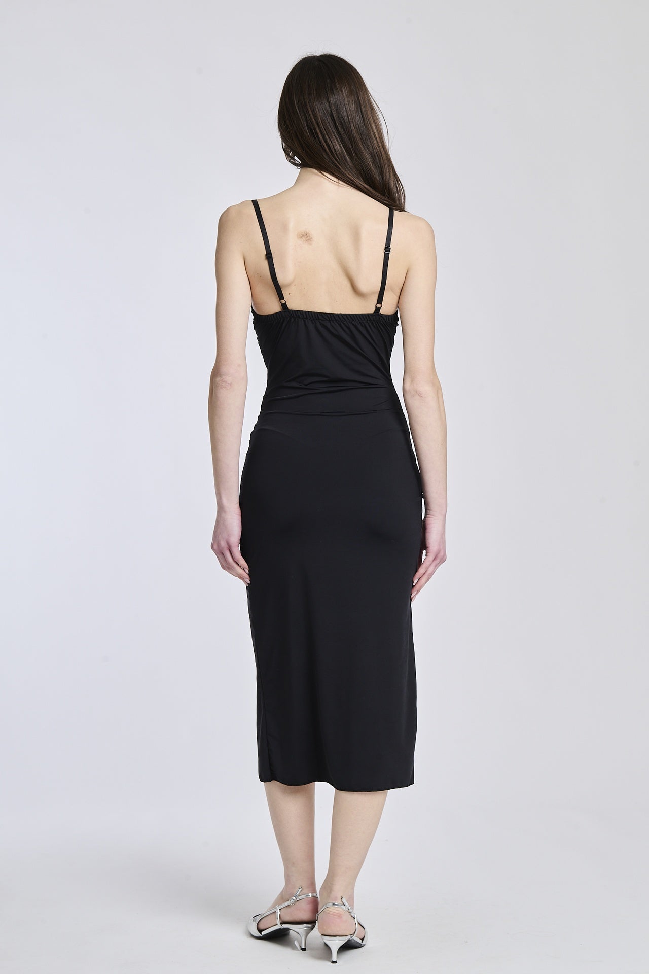 Abito nero a spalline sottili, tessuto lucido e apertura laterale per uno stile sexy e elegante.