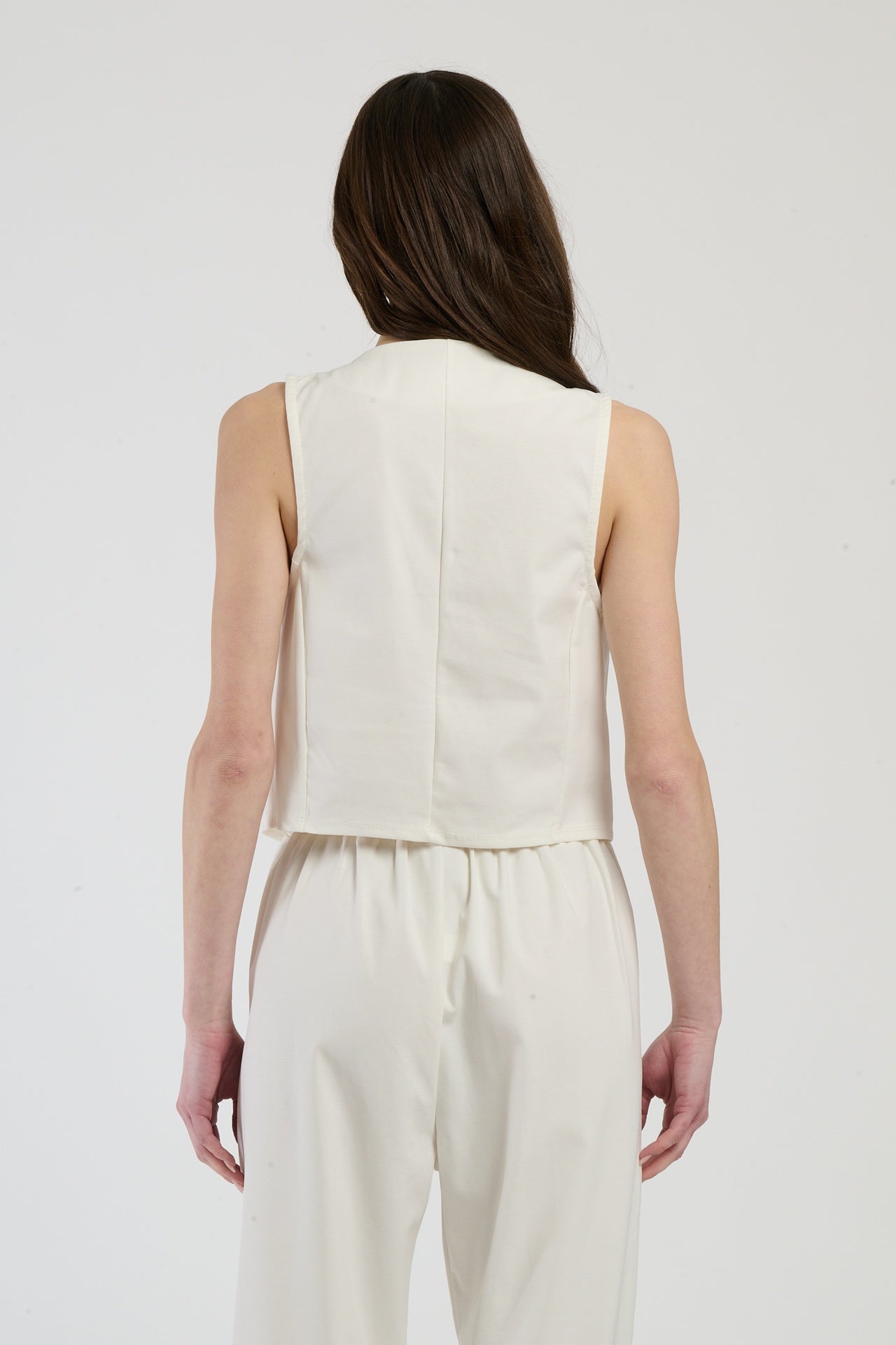 Completo bianco su una modella: gilet a bottoni e pantaloni