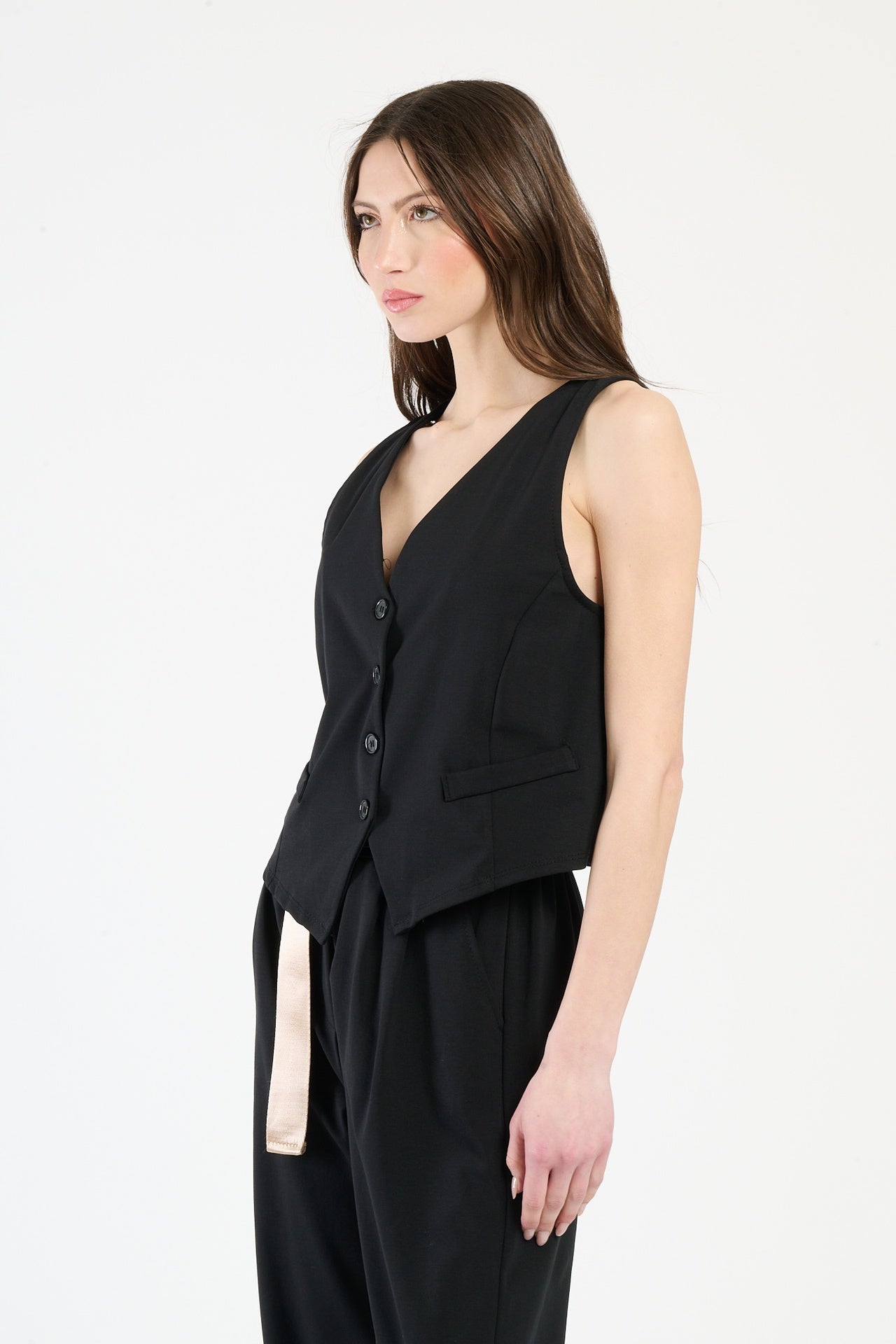 Modella in completo nero: gilet senza spalline e pantaloni, stile minimale e accattivante.