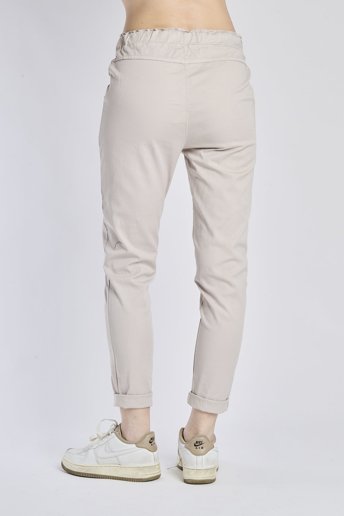 Donna con pantaloni beige a vita elastica, gamba dritta, perfetti per l’outdoor