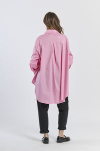 Outfit con camicia rosa larga e pantaloni neri, contrasto accattivante