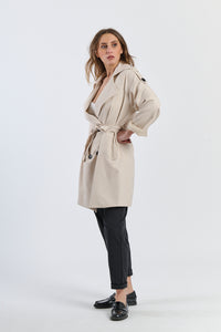 Trench beige con colletto alto, ideale per proteggersi dal vento con stile.