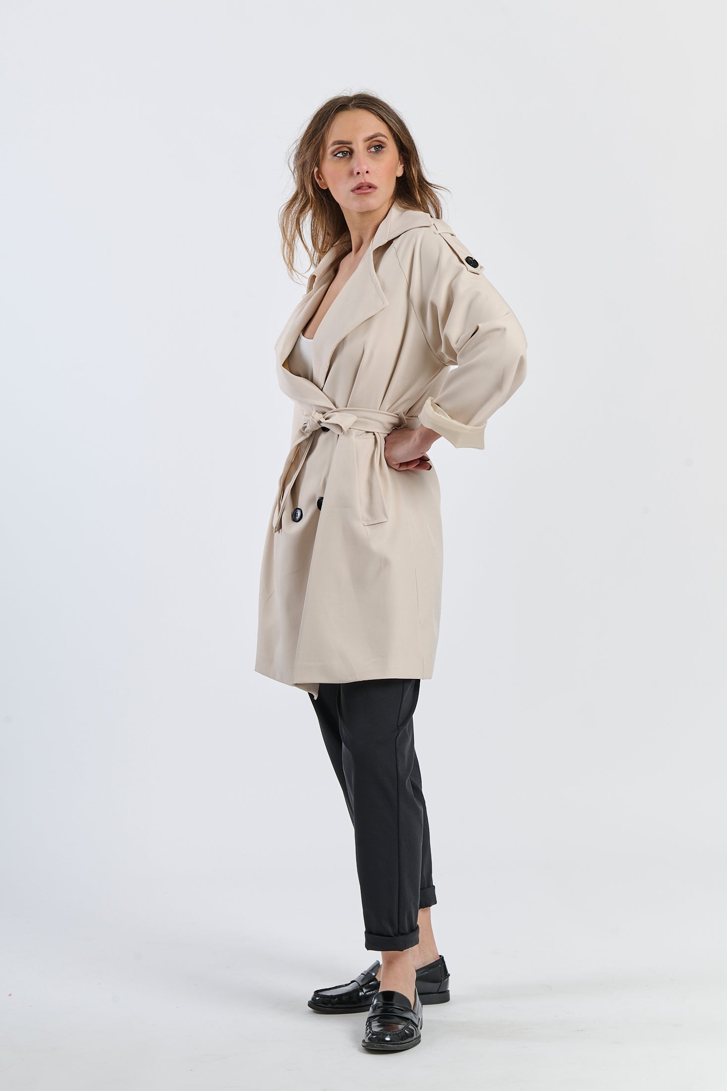 Trench beige con colletto alto, ideale per proteggersi dal vento con stile.