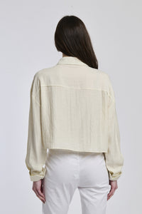 Donna veste una camicia a righe di un blu profondo e bianco, con un taglio leggermente oversize e maniche lunghe, che conferisce un senso di comfort e stile.