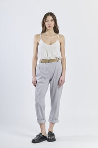 Look con top senza maniche rosa e pantaloni grigio chiaro ampi, eleganza sobria