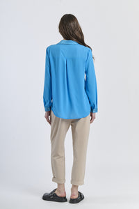 Outfit con camicia turchese e pantaloni neri, contrasto acido