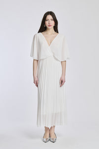 Un abito in bianco con lo stesso disegno crociato e maniche a mantello, creando un'atmosfera di chiarezza e eleganza