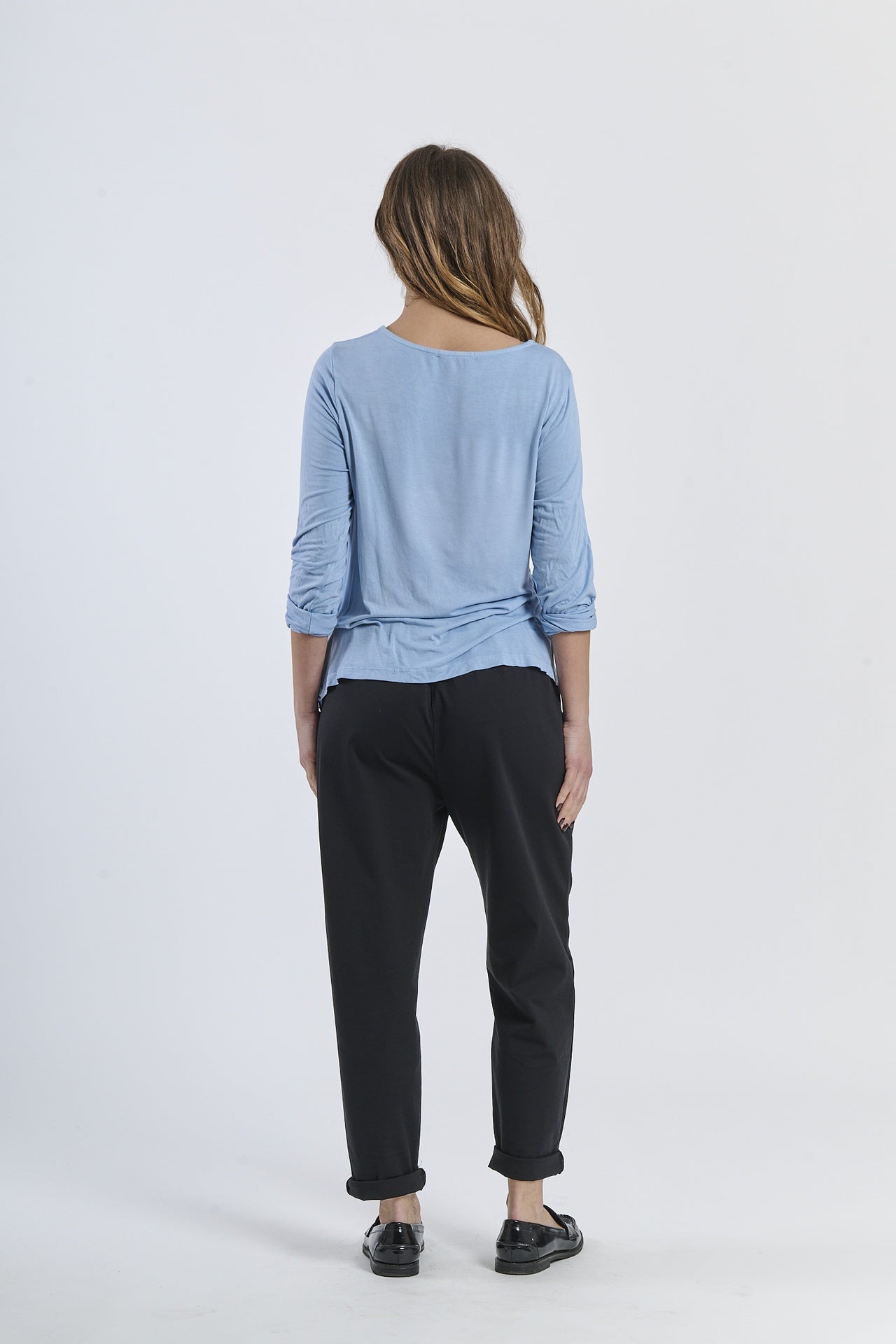 Blusa azzurra a maniche 3/4, abbinata a pantaloni neri, look urbano