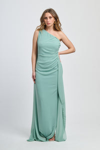 Abito lungo salvia, spalla singola, drappeggio fluido, accessorio decorativo sulla spalla.