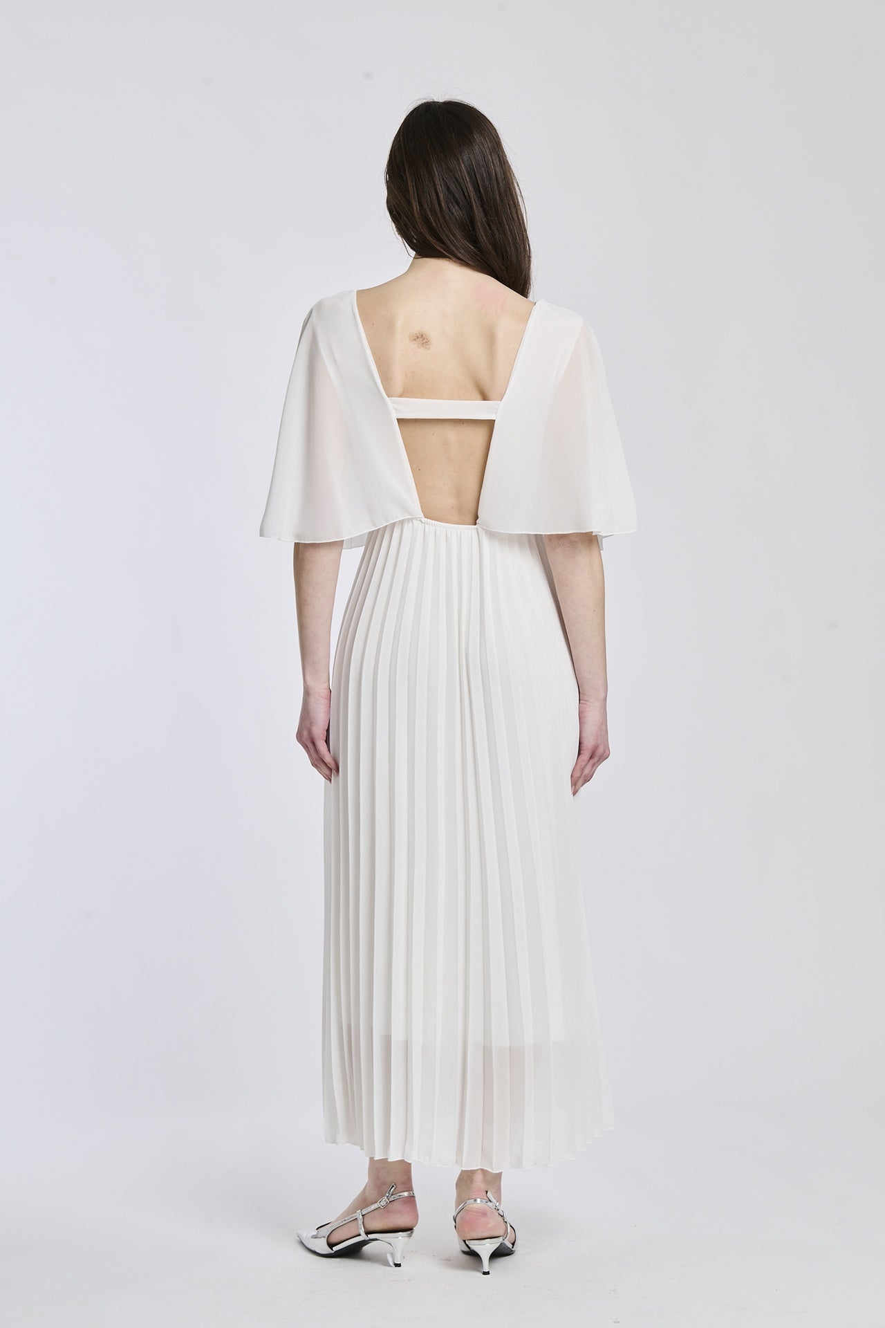 Vestito bianco con falde al fondo, mantenendo lo stile semplice e sofisticato, perfetto per occasioni formali.